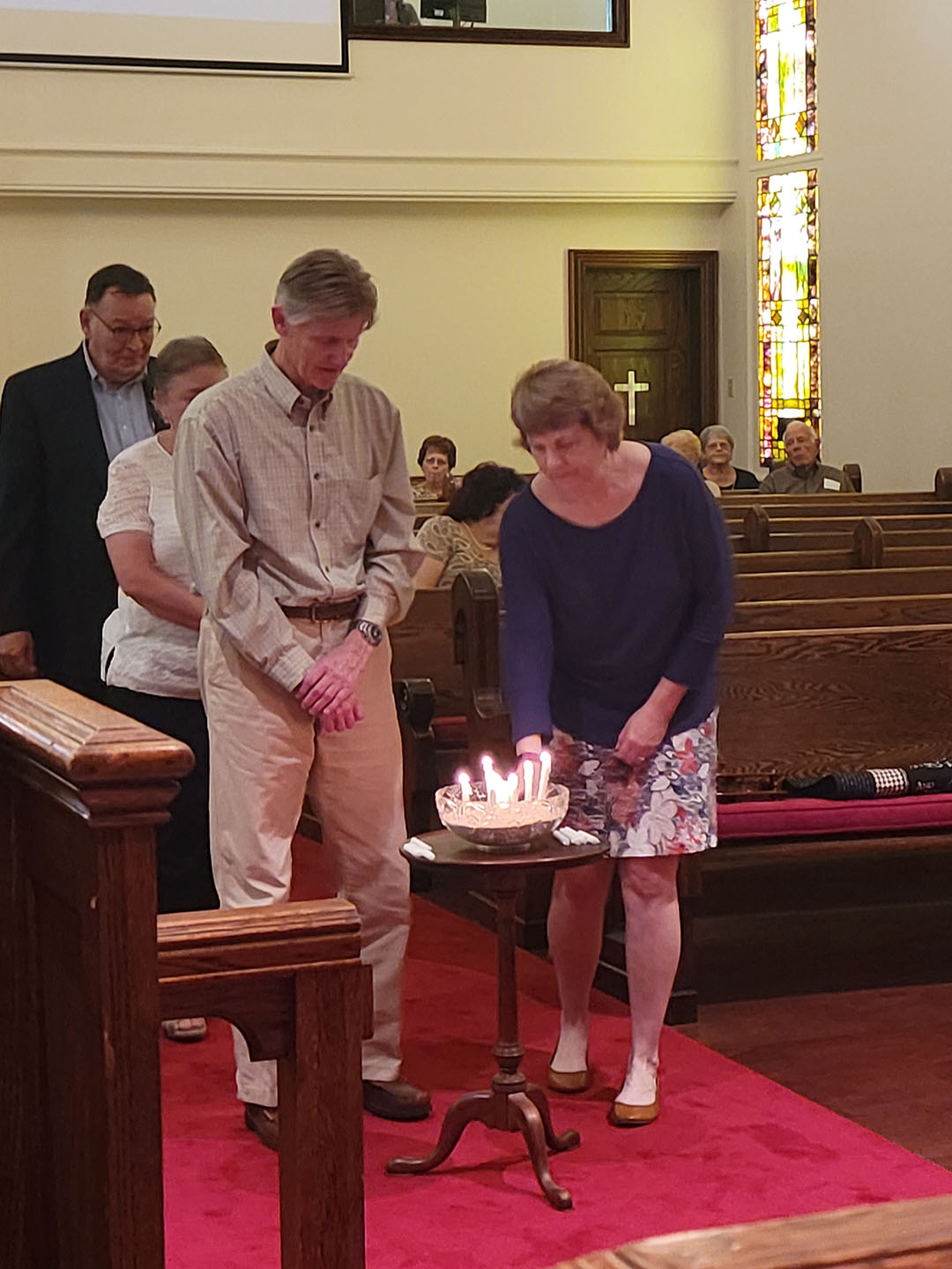 A couple approaches the lit candles to light another in memory of a loved one for All Saints Sunday. 